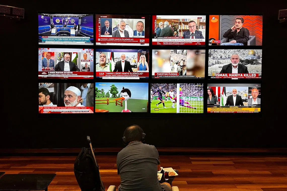 A person watches the news on multiple TV screens, most of them announcing the killing of senior Hamas leader Ismail Haniyeh, in Istanbul, Turkey, July 31, 2024. REUTERS/Alkis Konstantinidis/ File Photo