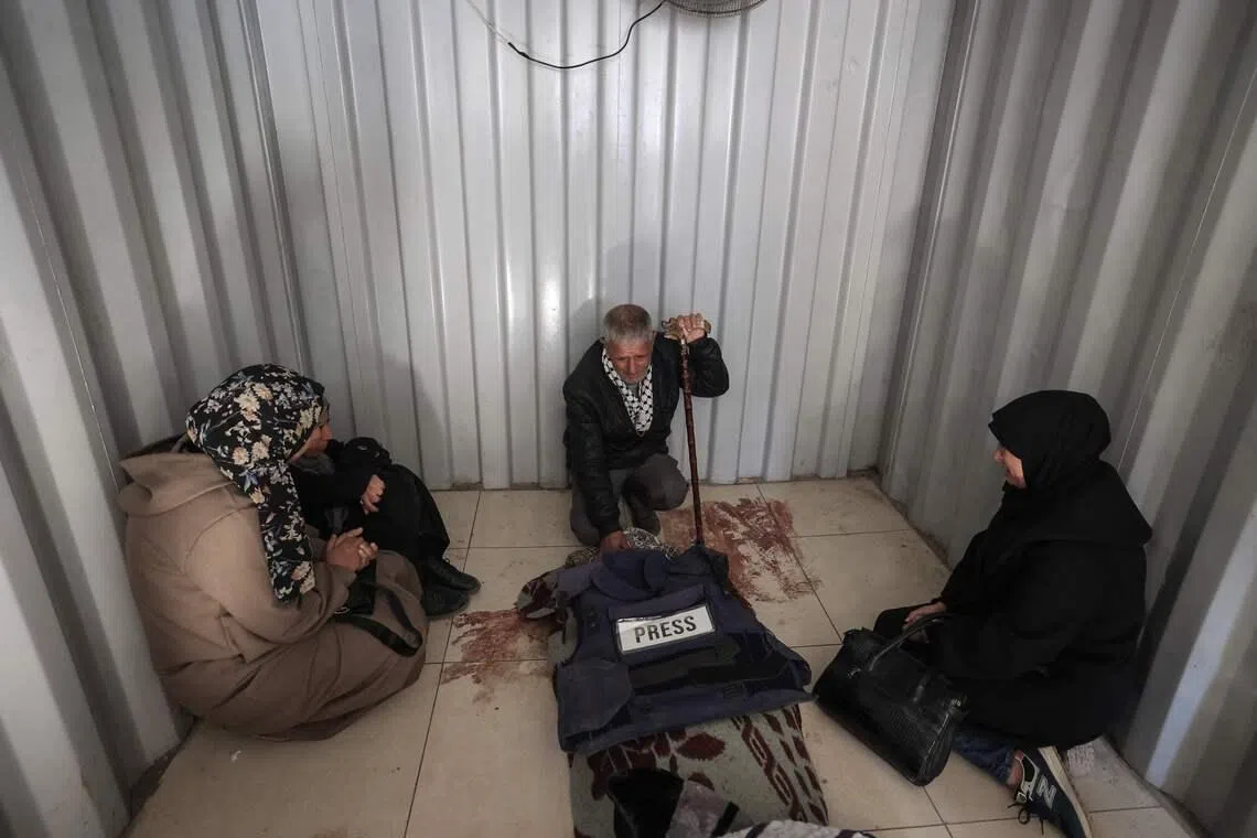 TOPSHOT - Relatives mourn over the body of journalist Amal al-Shamali, reportedly killed in an overnight Israeli strike, at al-Awda Hospital in the Nuseirat refugee camp, central Gaza Strip, on March 9, 2026. (Photo by Eyad Baba / AFP)