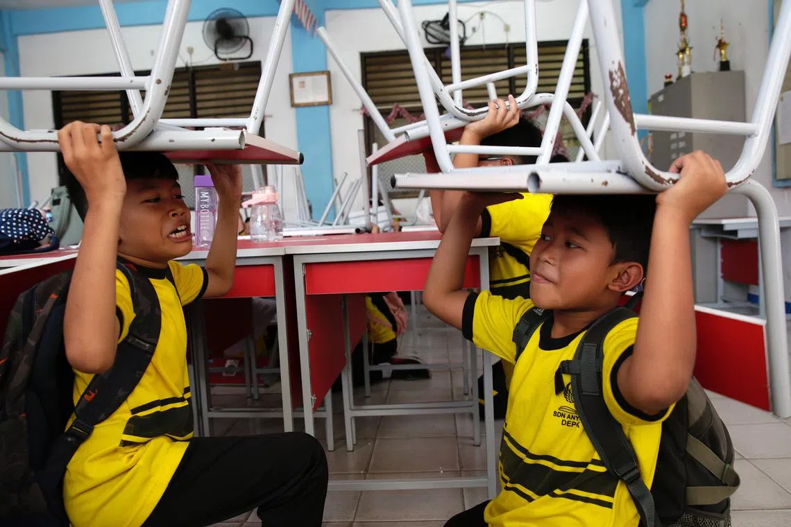 School students lifting chairs as they take cover during a disaster simulation at Anyelir 1 elementary school in Depok, Indonesia on July 20, 2023. The National Disaster Management Agency noted that there were 988 natural disasters that hit Indonesia from January to May  2023, 11 of which were earthquakes, and dozens of fires and floods in various cities in Indonesia.  