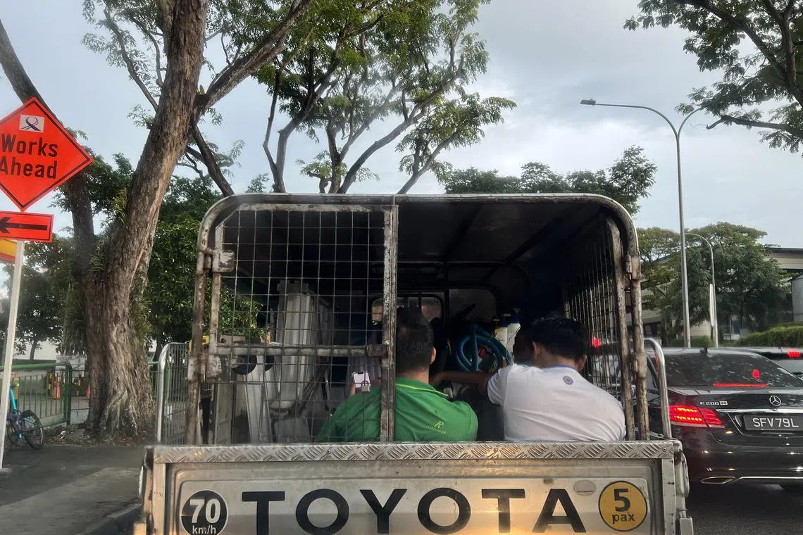 Workers sitting at the back of a lorry. 