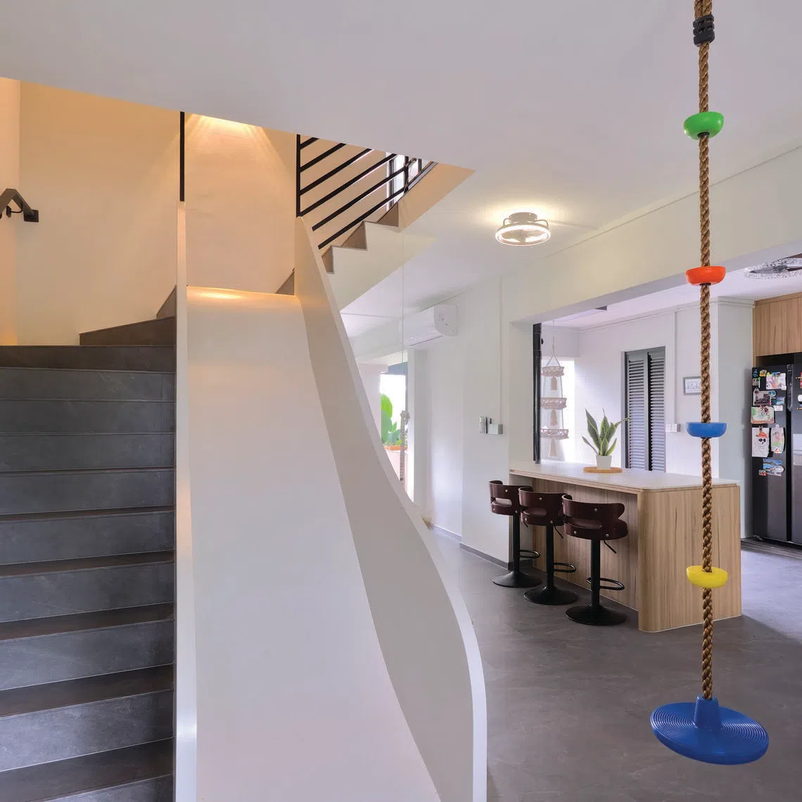 Colourful playground elements inject a cheerful touch into a family's neutral-toned executive maisonette.