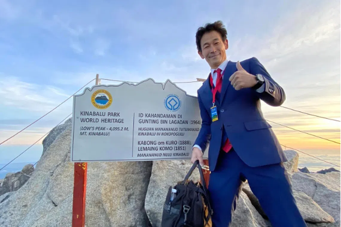 Japanese tailor and adventurer Nobutaka Sada at the summit of Mount Kinabalu, in a business suit.