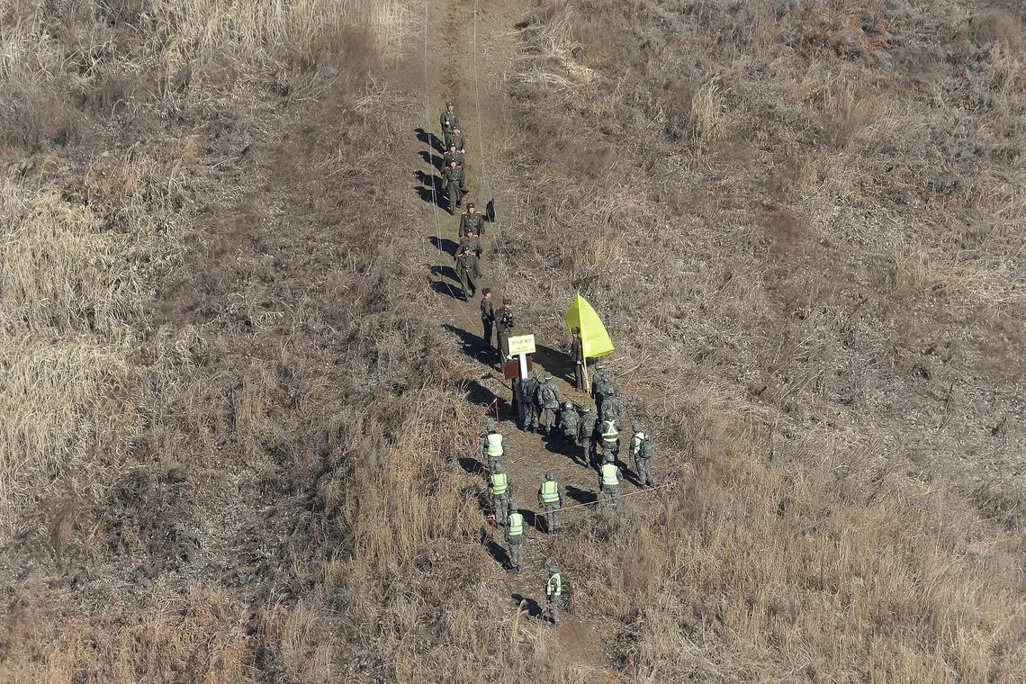 FILE PHOTO: North Korean army soldiers, top, head to cross the Military Demarcation Line inside the Demilitarized Zone (DMZ) to inspect the dismantled South Korean guard post as South Korean army soldiers watch in the central section of the inter-Korean border in Cheorwon, December 12, 2018. Ahn Young-joon/Pool via REUTERS/File Photo