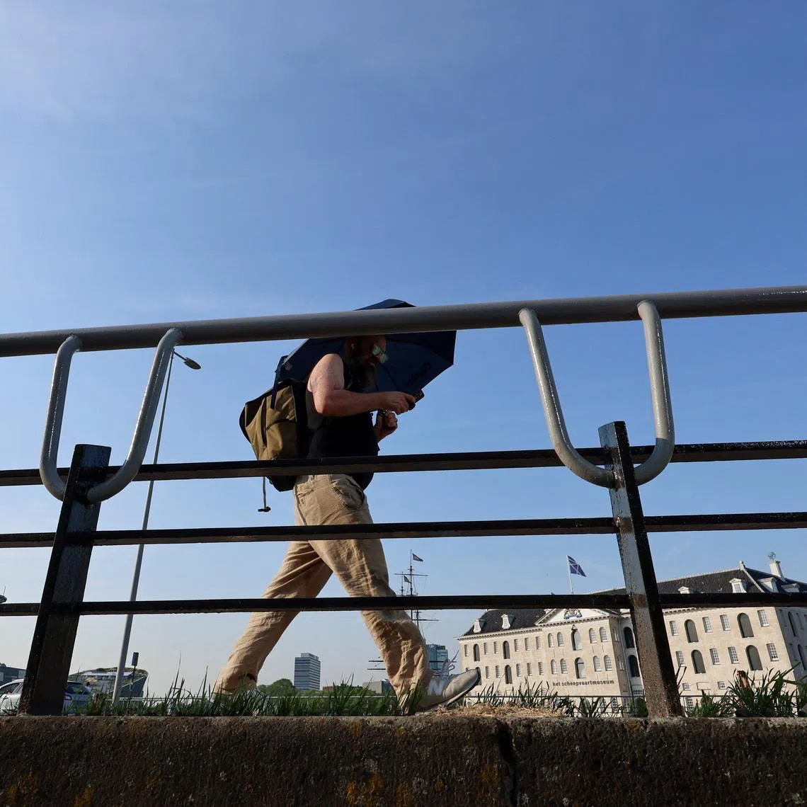 A man walks with an umbrella in Amsterdam, during the heatwave hitting the country, while a code red alert is issued, in Amsterdam, the Netherlands, June 26, 2026. REUTERS/Nicolas Economou