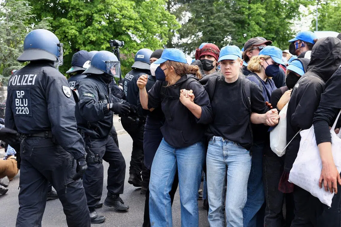 Activists form a human chain next to police forces during a protest against the expansion of the Tesla Gigafactory in Gruenheide near Berlin, Germany, May 10, 2024. REUTERS/Christian Mang
