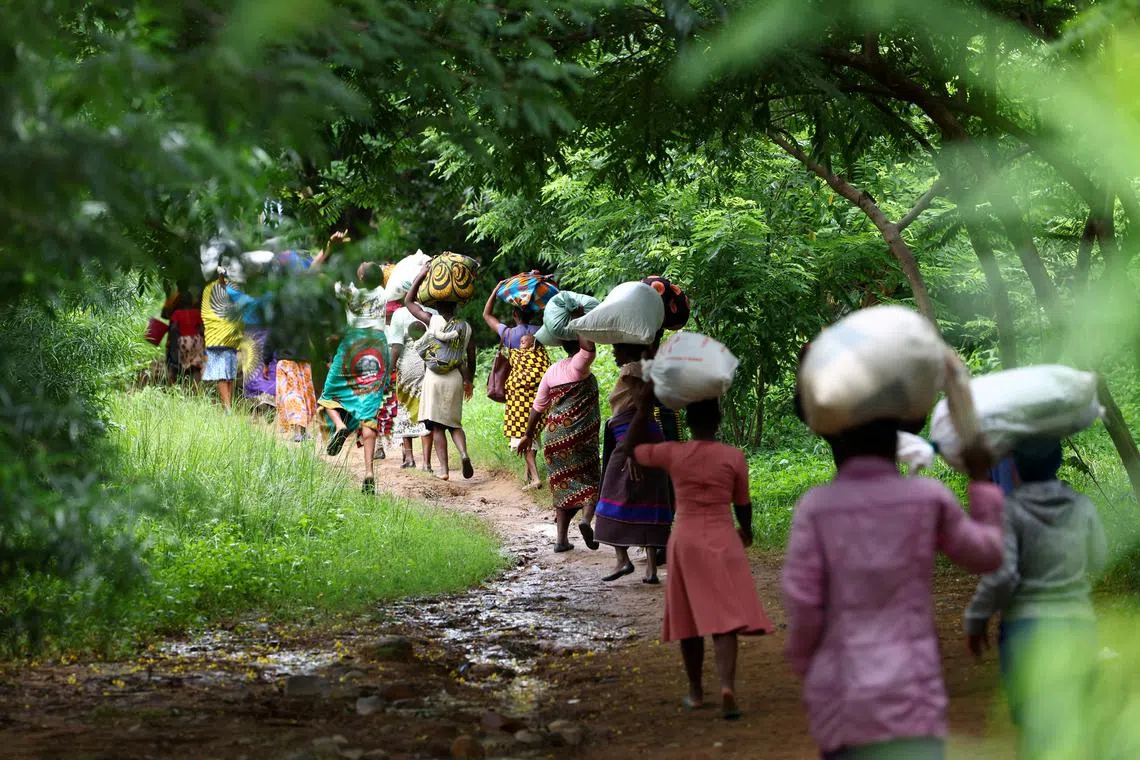 FILE PHOTO: Flood victims from Mtauchira village carry food they received from the Malawi government in the aftermath of Cyclone Freddy that destroyed their homes in Blantyre, Malawi, March 16, 2023. REUTERS/Esa Alexander/File Photo