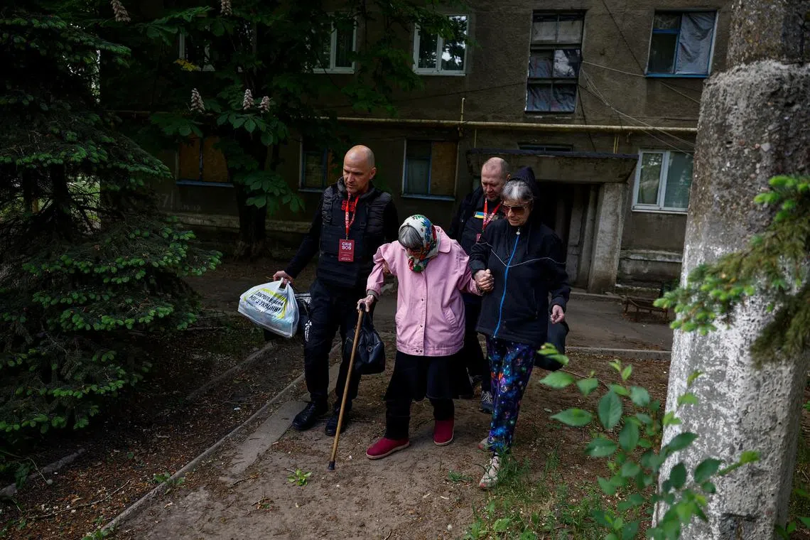 Oleksandr and Vladyslav, volunteers of the EastSOS non-government organisation, assist local resident Valentyna Sharonova, 88-year-old and her daughter Anzhelika, 57-year-old, during their evacuation from the town of Toretsk, amid Russia's attack on Ukraine, near a front line in Donetsk region, Ukraine May 8, 2024. REUTERS/Valentyn Ogirenko
