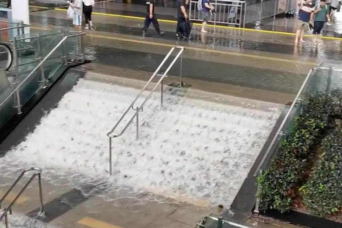 Flood water flowing down a flight of stairs as people walk nearby, in Wuxi, Jiangsu province.