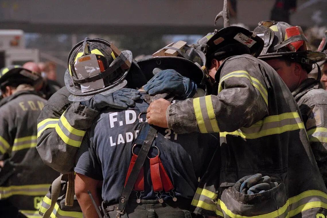 A firefighter is comforted by his colleagues after losing a kin, also a firefighter, in the Sept 11, 2001 terrorist attacks.