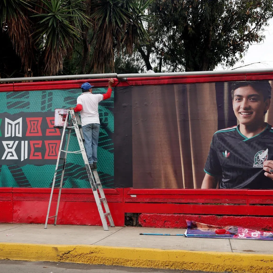 A worker is pictured painting billboards outside the Estadio Azteca ahead of the match.
