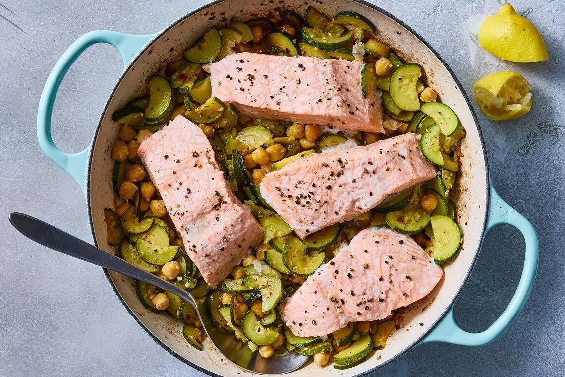 Salmon with olive oil-braised zucchini and chickpeas. Slow-cooking zucchini in garlicky olive oil intensifies their natural sweetness and gives them a silky texture. Food styled by Barrett Washburne. (Bryan Gardner/The New York Times)