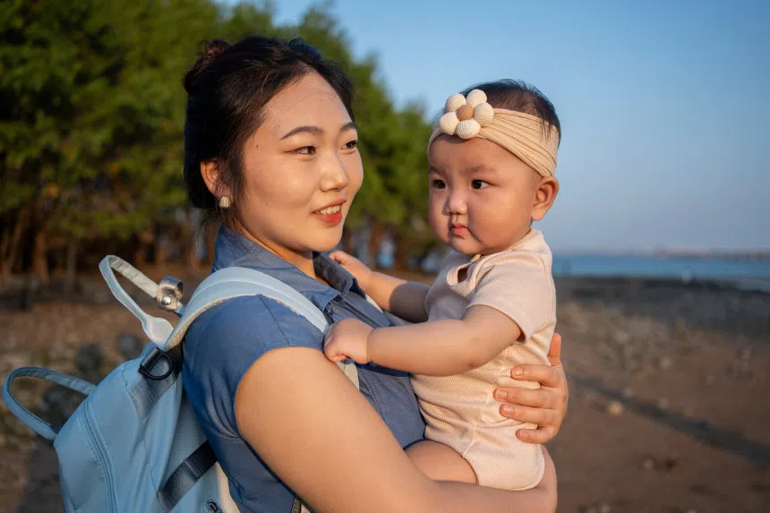 Best diaper bags in Singapore: Mother carrying a baby, wearing a diaper bag backpack
