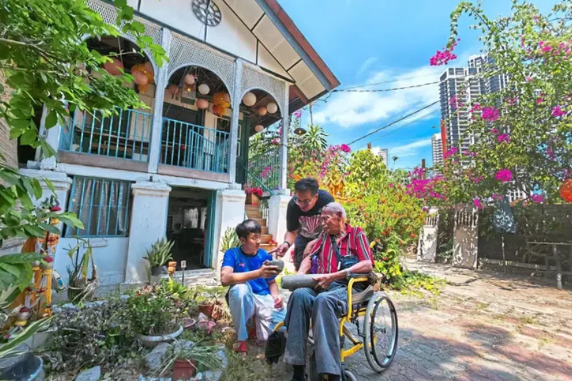 Fourth-generation resident Nai Boon Phrom Sararaksh with his father Ninn Sararaksh (on wheelchair) and son at their double-storey house in Kampung Siam. 
