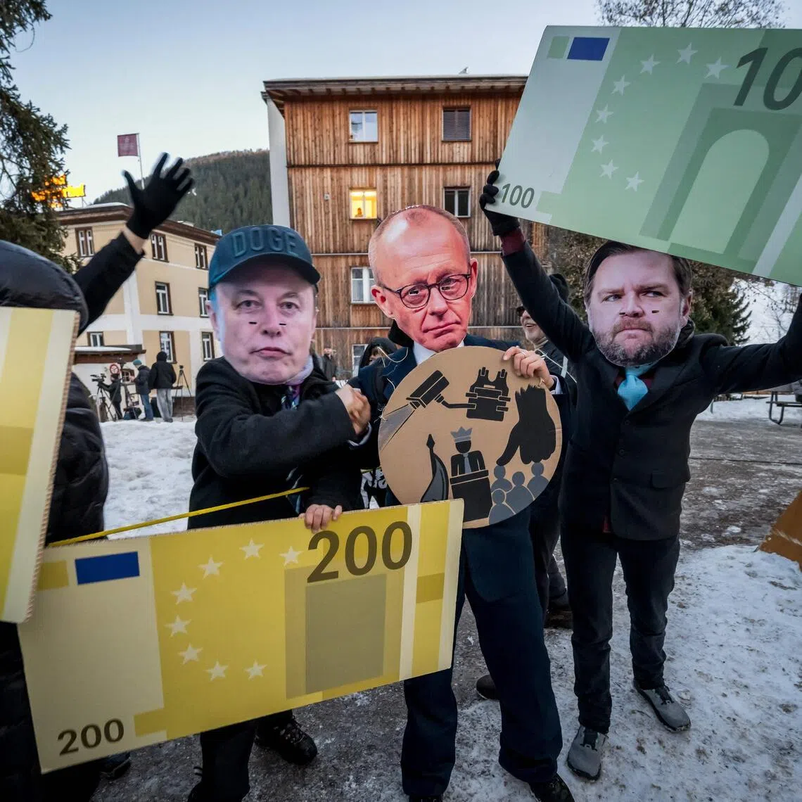  Protesters wearing a mask of Tesla CEO Elon Musk, Germany's Chancellor Friedrich Merz and US Vice-President J.D. Vance hold cardboard cut-out euro banknotes while taking part in a demonstration against the World Economic Forum. 
