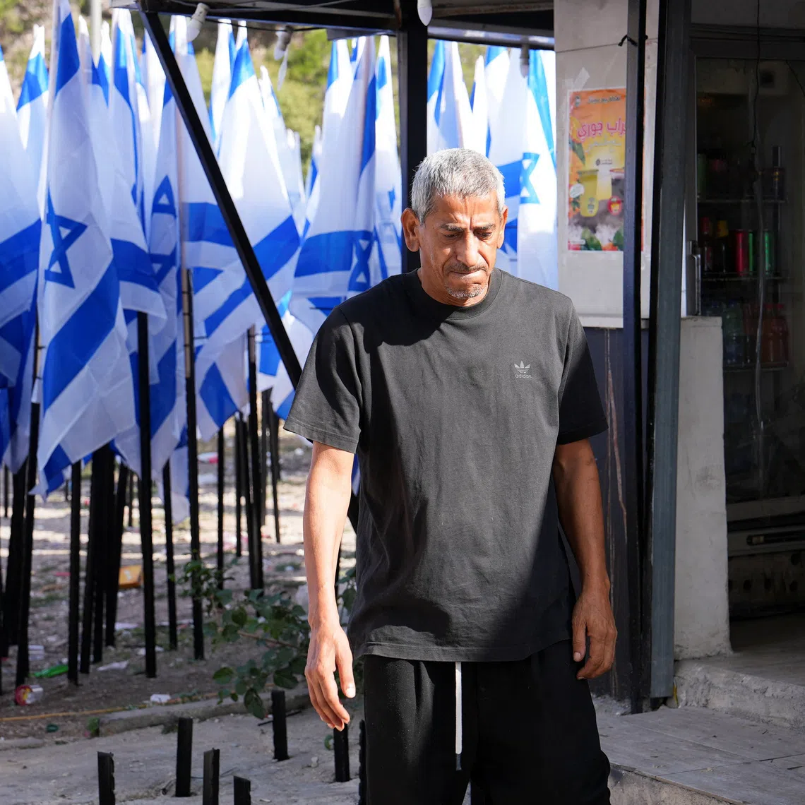 Palestinian coffee shop owner Mueiyyid Hussein outside his  business in the Israeli-occupied West Bank on Oct 9. Israeli settlers have planted dozens of Israeli flags at the entrance to his streetside cafe.