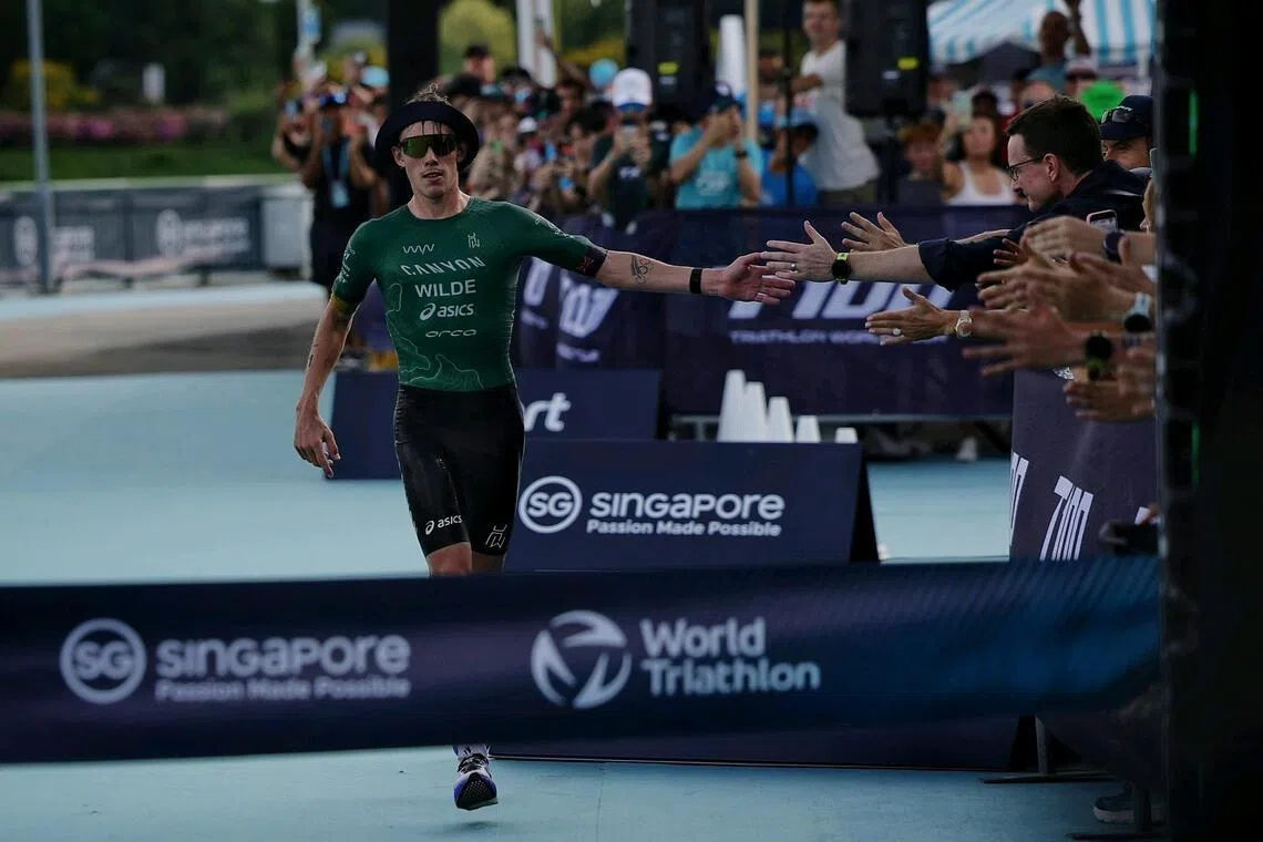 Defending champion Hayden Wilde of New Zealand acknowledging the fans as he approaches the finish line to win the Singapore T100 pro race on April 25, 2026.