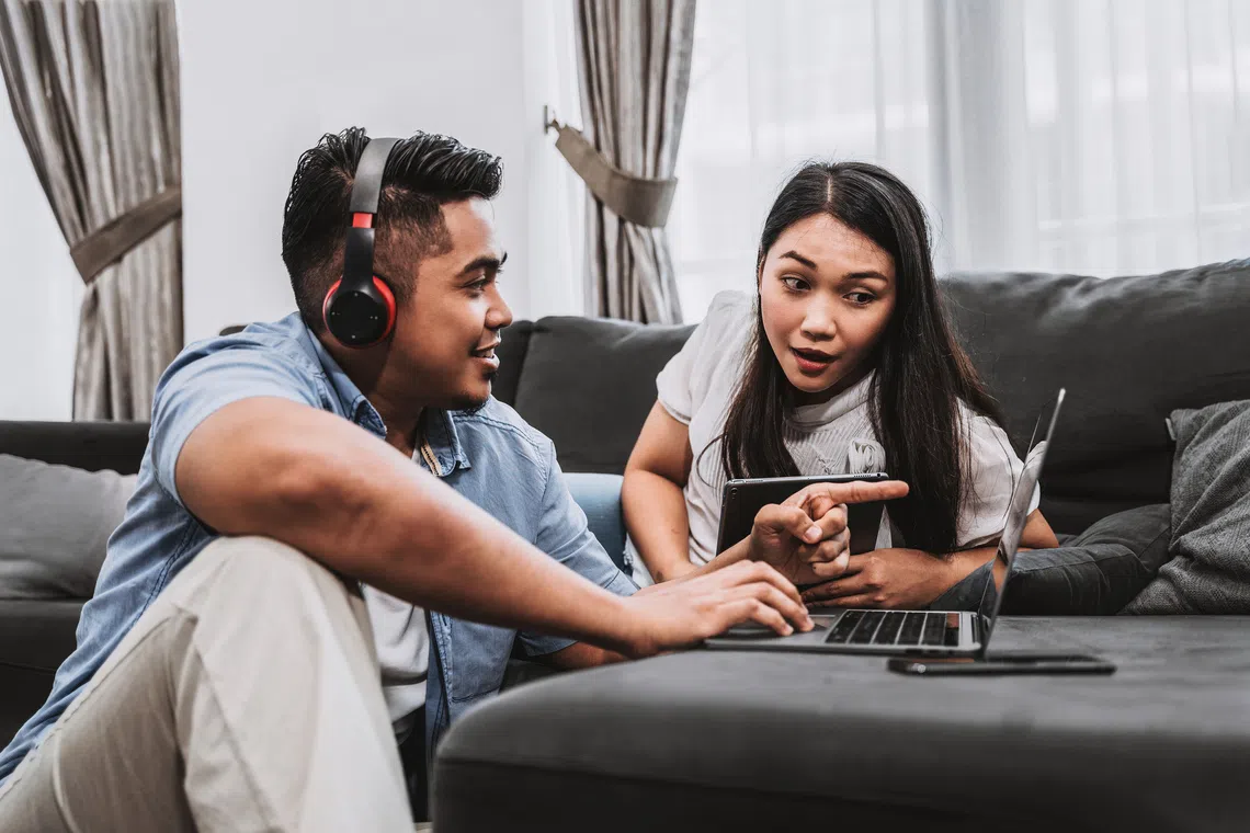 young couple using devices connected seamlessly to internet with singtel wifi 7 best home fibre broadband plan in singapore