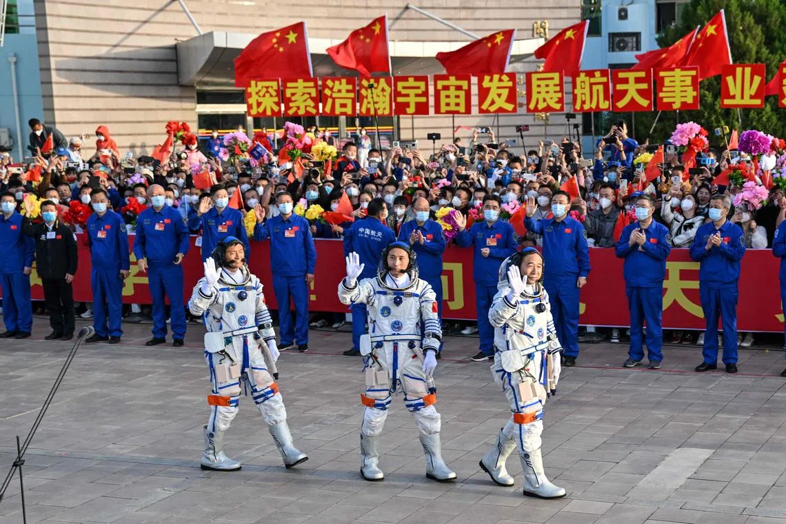 Taikonauts Gui Haichao (L) payload expert, Zhu Yangzhu (C) space flight engineer and commander Jing Haipeng (R) waving before boarding a Long March-2F carrier rocket, carrying the Shenzhou-16 Manned Space Flight Mission, at the Jiuquan Satellite Launch Centre in China's northwestern Gansu province on May 30, 2023. 