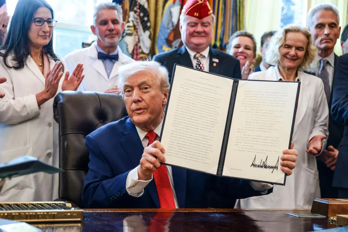 President Donald Trump holds a signed executive order in the Oval Office at the White House in Washington, D.C., U.S., December 18, 2025. REUTERS/Evelyn Hockstein