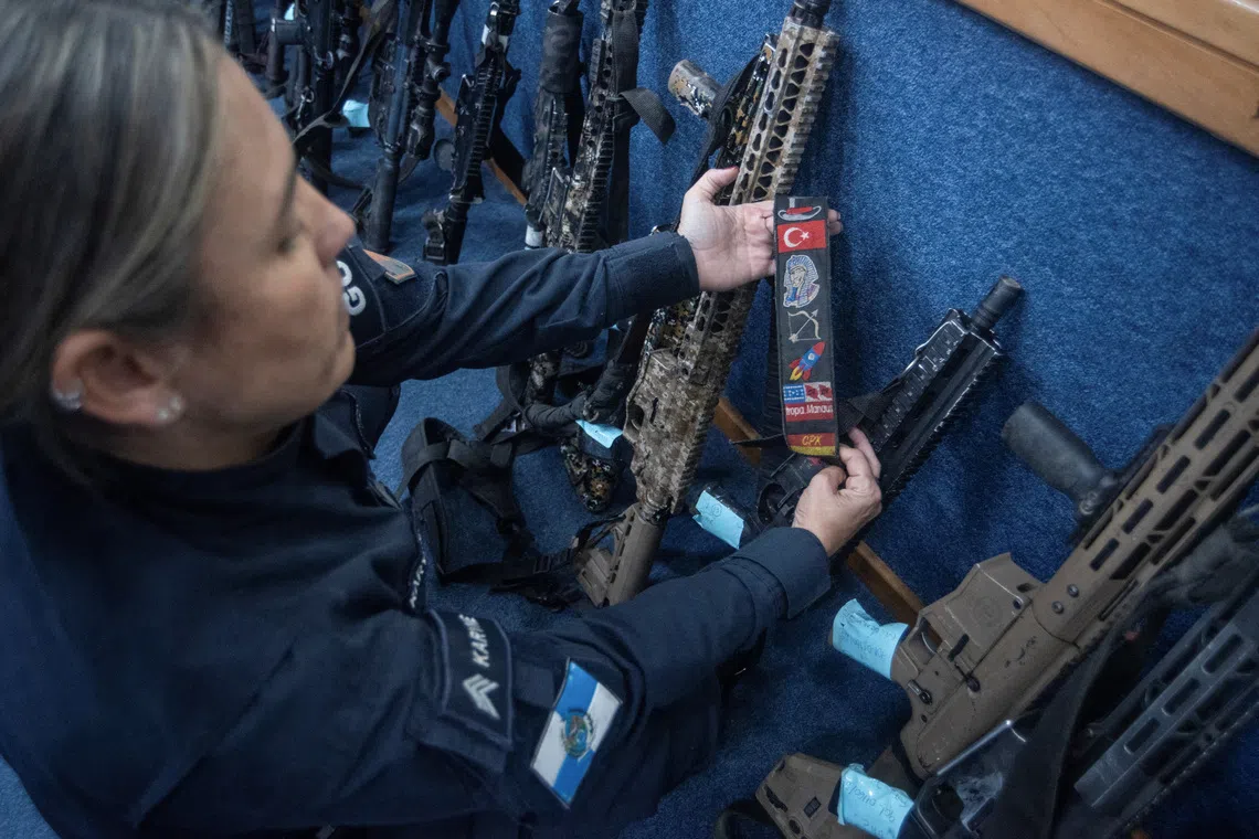 An official displays seized weapons with gang insignia during a press conference, which the police said were captured during what was the deadliest police operation in Brazil's history, in Rio de Janeiro, Brazil, October 29, 2025. REUTERS/Tita Barros