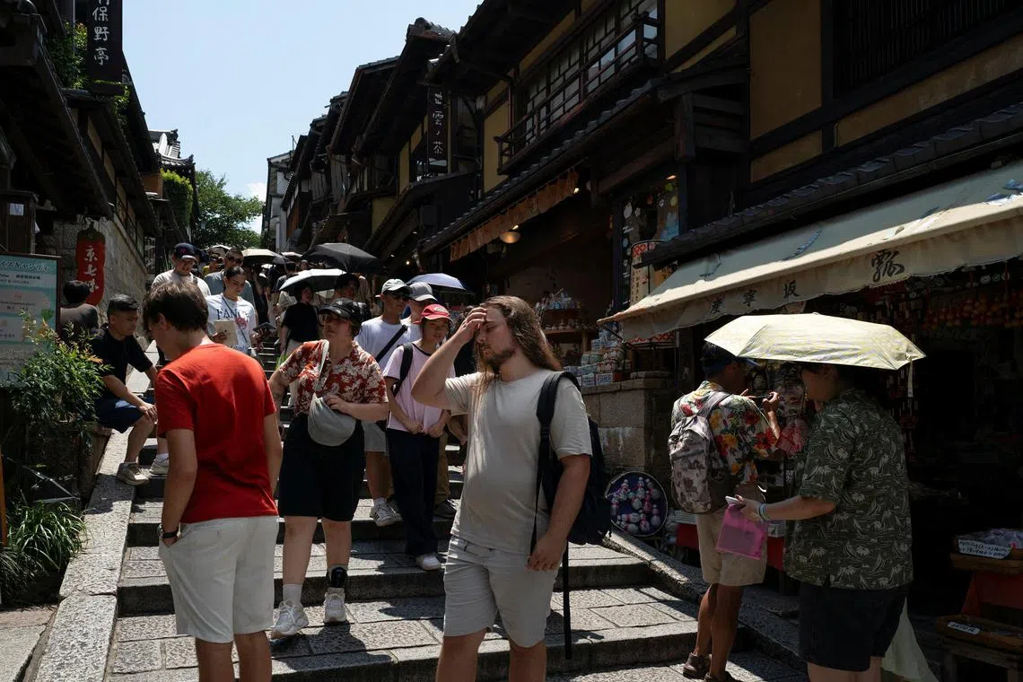FILE PHOTO: Tourists exposed to the sun walk through a traditional alleyway near Kiyomizu-dera temple in Kyoto, Japan August 3, 2025. REUTERS/Fred Mery/File Photo