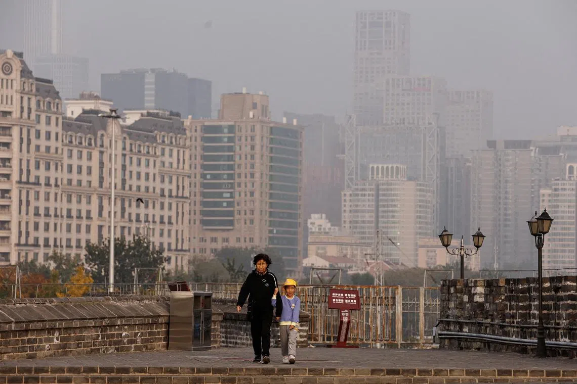 FILE PHOTO: People walk at the Ming Dynasty City Wall Relics Park, as Beijing issues orange alert for heavy air pollution, in Beijing, China October 31, 2023. REUTERS/Tingshu Wang/File Photo
