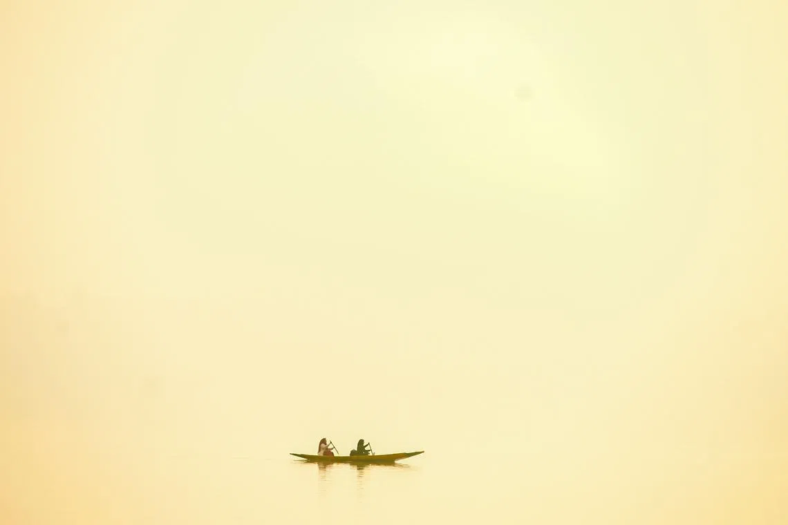 Women row a boat in the waters of Dal Lake amid foggy conditions in Srinagar on November 2, 2022.
