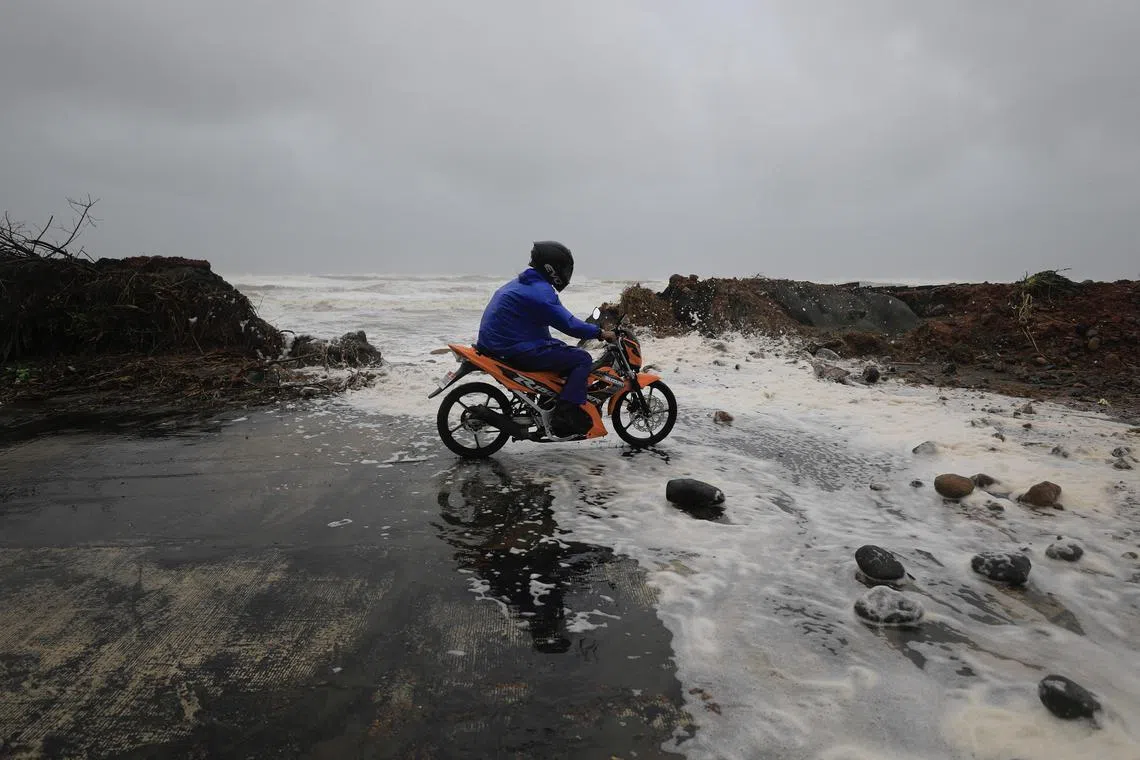 A motorcycle rider crosses a damaged storm surge barrier in the coastal town of Aparri, Cagayan province, Philippines, on Nov 7, 2024.
