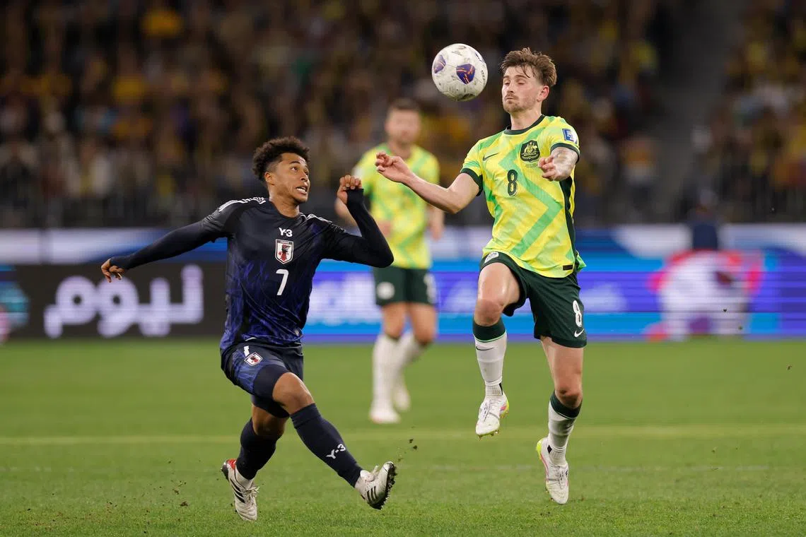 onnor Metcalfe of Australia controls the ball under pressure from Joel Chima Fujita of Japan during the World Cup qualifier.