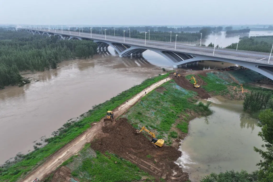 Workers carrying out reinforcement operations on an embankment of a river in Hebei on Aug 4.