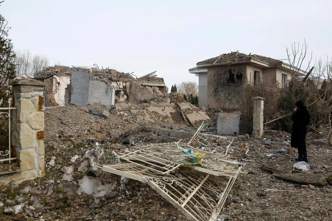 A woman looks at houses heavily damaged by a Russian missile strike, amid Russia's attack on Ukraine, in Kyiv region, Ukraine February 22, 2026. REUTERS/Valentyn Ogirenko