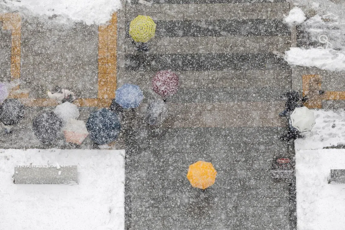 Pedestrians crossing a street in the business district amid heavy snowfall in Seoul on Nov 27, 2024. 