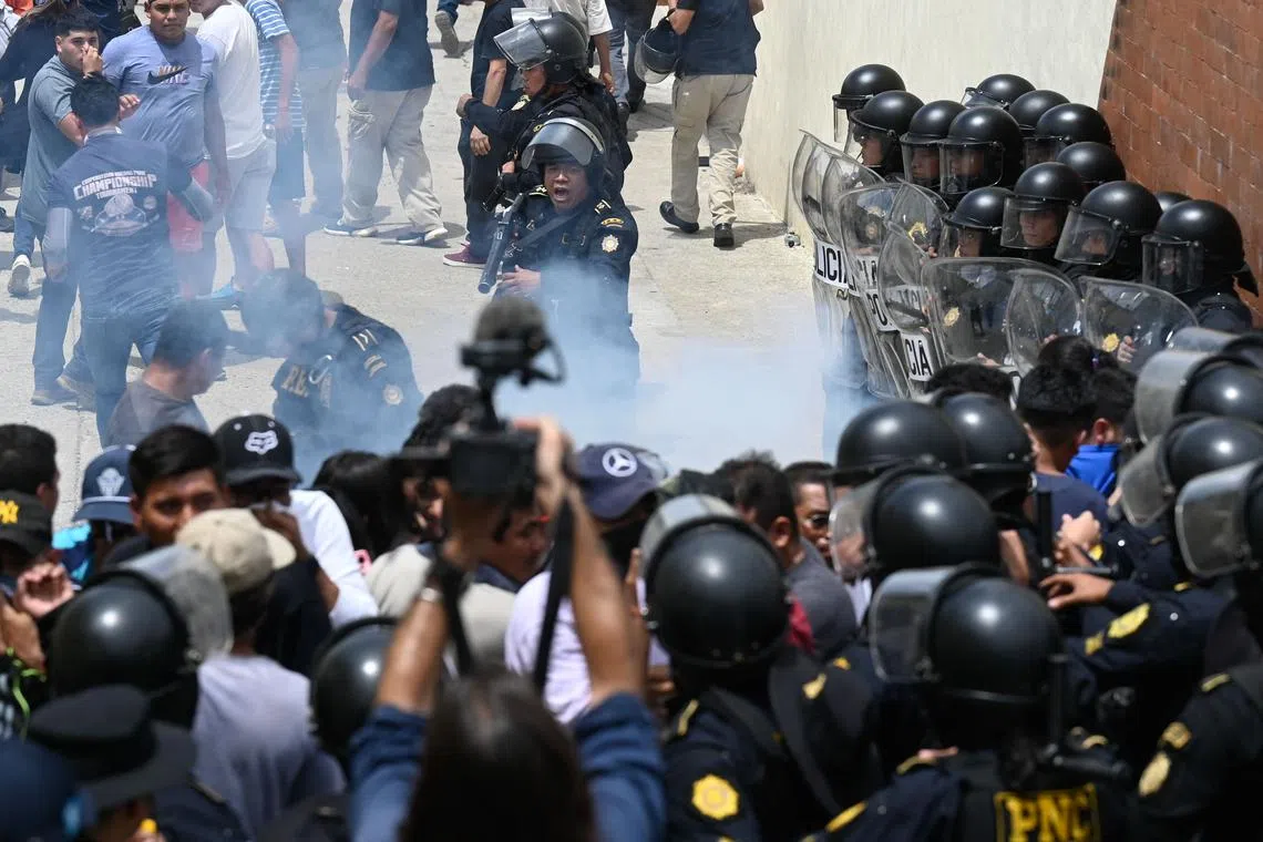 A police officer fires tear gas to disperse protesting voters outside a polling station which remains closed following alleged threats and irregularities during general elections, in San Jose del Golfo, on the northern outskirts of Guatemala City on June 25, 2023. 