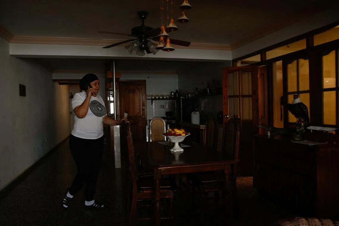 A resident of Cuba talks on the phone during a power cut on April 8, 2026, saving her energy backup system for when it is needed.