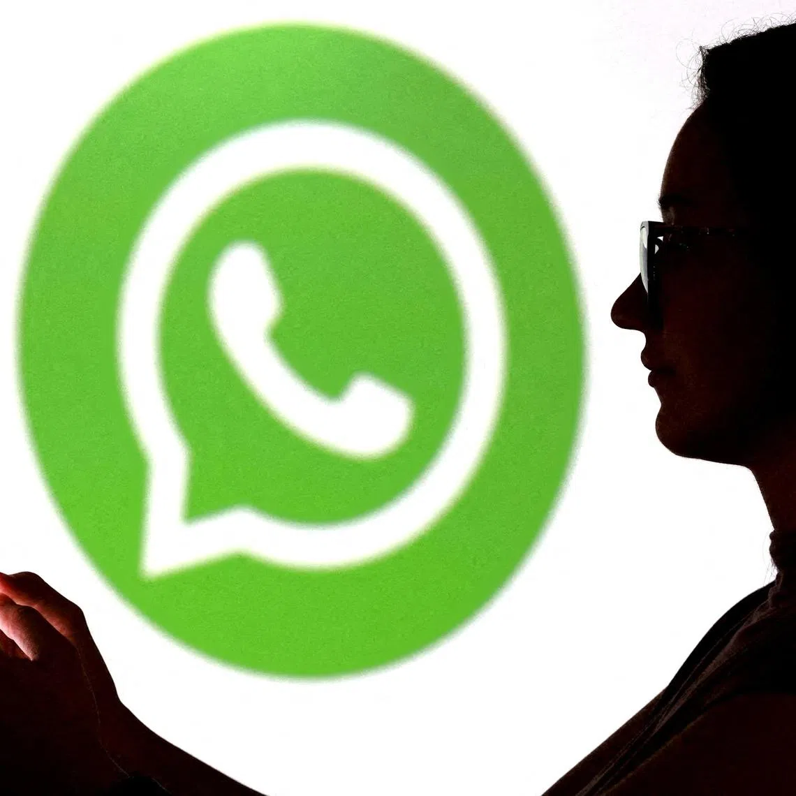 FILE PHOTO: A teenager poses for a photo while holding a smartphone in front of a Whatsapp logo in this illustration taken September 11, 2025. REUTERS/Dado Ruvic/Illustration/File Photo