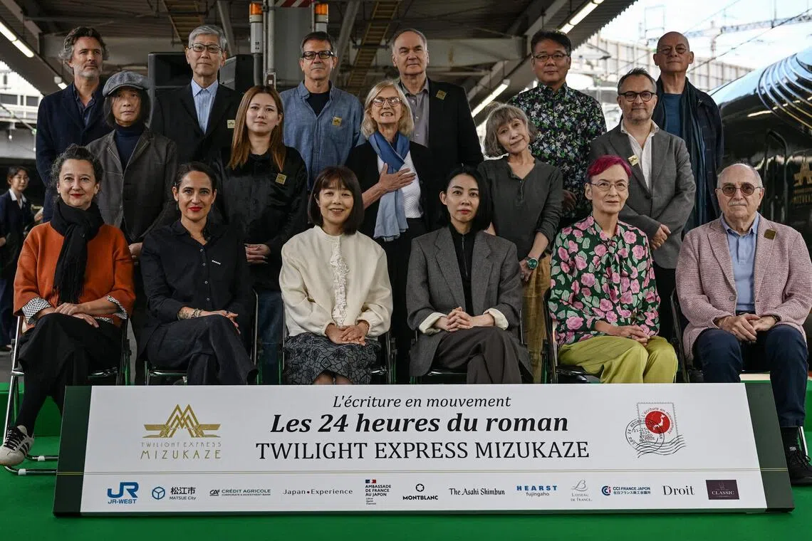 (From L, front) French novelist Muriel Barbery, French writer Claire Berest, Japanese writer Machi Tawara, Japanese writer Mariko Asabuki, Japanese author Anna Ogino, French writer Paul Fournel and (From L, middle) Japanese writer Hitonari Tsuji, Japanese novelist Hitomi Kanehara, "L'Ecriture en mouvement" Association Founder Anne Forrest-Wilson, Japanese author Kaori Ekuni, French poet Frederic Forte and (From L, rear) French writer Christophe Ono-dit-Biot, Japanese poet Hisaki Matsuura, Argentine writer Eduardo Berti, French writer Herve Le Tellier, Japanese author Toh EnJoe, French author Richard Collasse pose for a group photo at Shin-Osaka station in Osaka prefecture on October 22, 2026. Sixteen writers -- half French-speaking and half Japanese -- boarded a luxury train in Kyoto on October 22, 2026, faced with the unusual task of collectively writing a novel in under 24 hours. (Photo by Rie KIKUCHI / AFP) / To go with 'JAPAN-FRANCE-LITERATURE-TRANSPORT-TOURISM' Reportage by Julien GIRAULT
