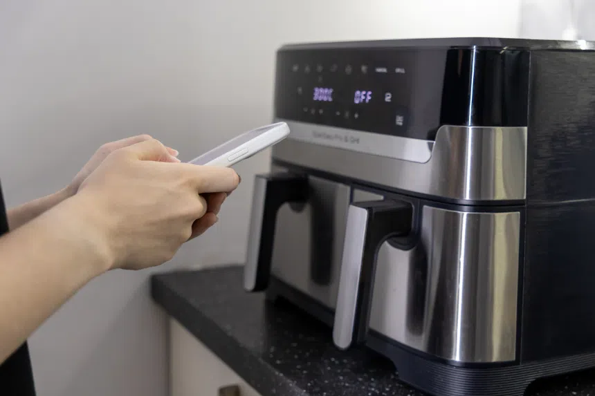 Best dual air fryers in Singapore: Person using their phone to control air fryer settings