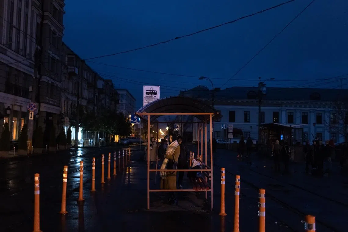 A woman waits for a tram in the Podil neighborhood as blackouts continue in downtown Kyiv.