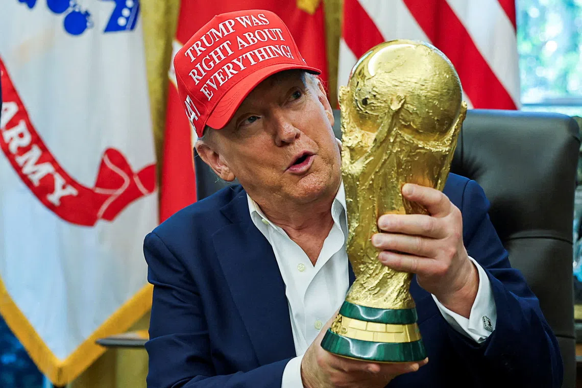 FILE PHOTO: U.S. President Donald Trump wears a 'Trump Was Right About Everything!' hat while holding the FIFA World Cup Trophy, as he makes an announcement on the 2026 FIFA World Cup, in the Oval Office at the White House in Washington, D.C., U.S., August 22, 2025. REUTERS/Jonathan Ernst/File Photo