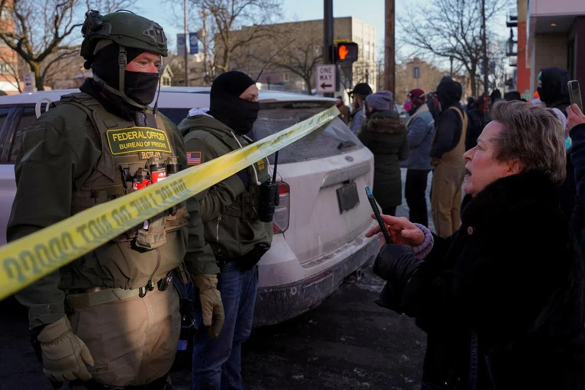 FILE PHOTO: Federal agents stand behind police tape as people gather near the site where a man identified as Alex Pretti was fatally shot by federal agents trying to detain him, in Minneapolis, Minnesota, U.S., January 24, 2026. REUTERS/Seth Herald/File Photo