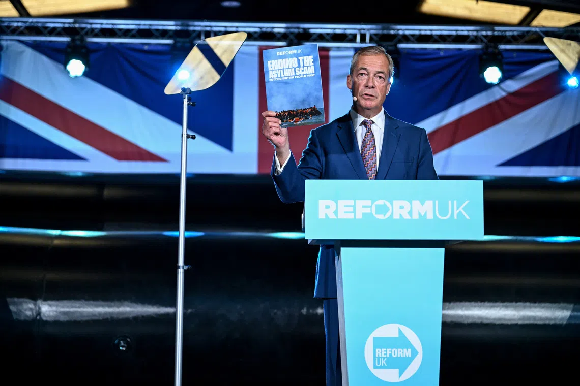 Britain's Reform UK leader Nigel Farage holds a document titled \"ending the asylum scam, putting British people first\" during a press conference, with a model of a dinghy visible in the background, in Hythe, Kent, Britain, October 12, 2026. REUTERS/Chris J Ratcliffe