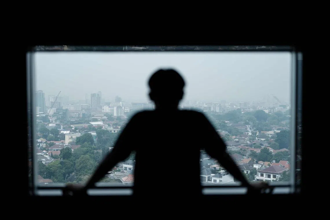 An Indonesian forced to work as a scammer in Cambodia looks through a window as recounts his experience to a journalist.
