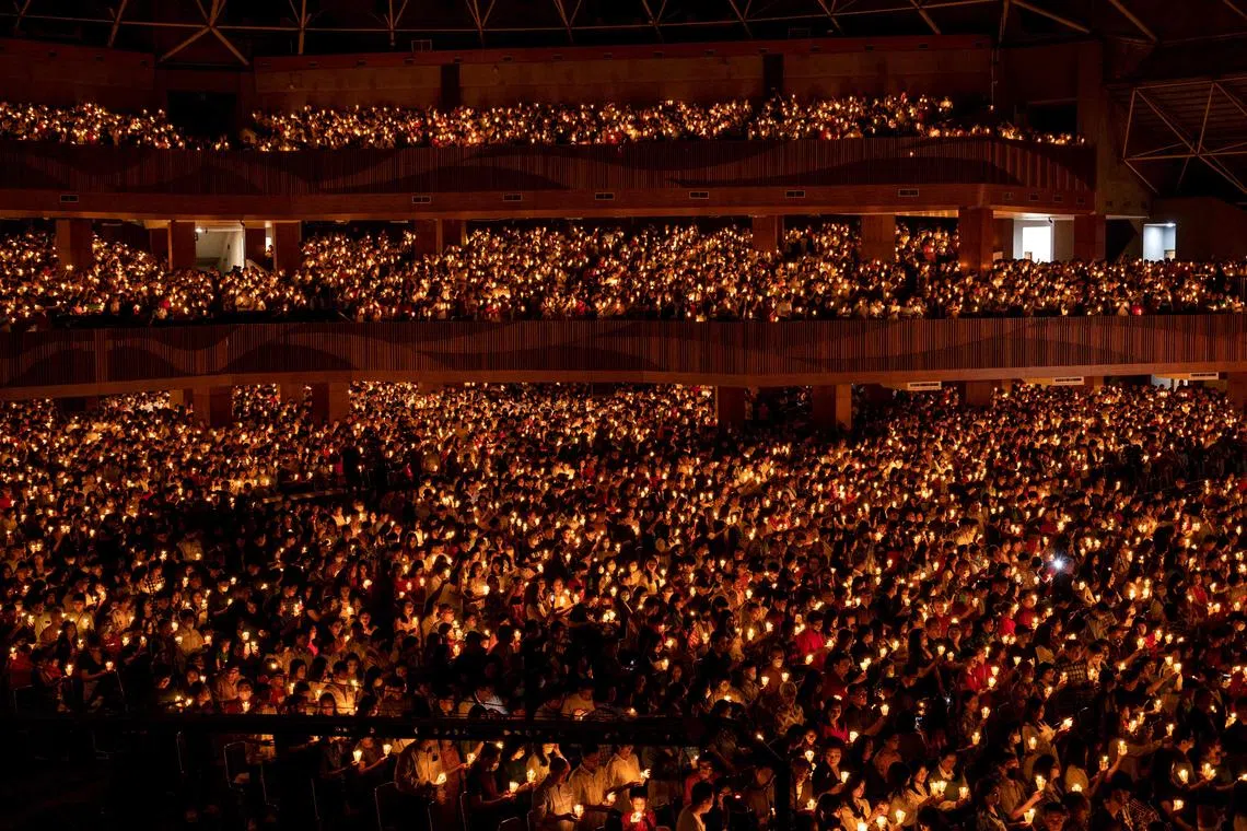 Christian devotees holding candles during a midnight mass on Christmas Eve at the Bethany church in Surabaya on Dec 24, 2023. 