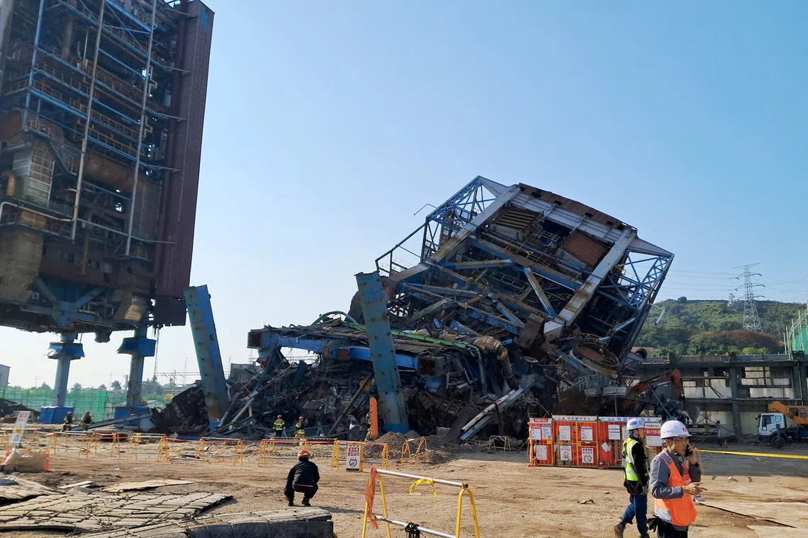 People walk near a large structure which collapsed and where multiple people are believed to be trapped, at the Korea East-West Power's Ulsan Power Plant headquarters, in Ulsan, South Korea, November 6, 2025.     Yonhap/via REUTERS