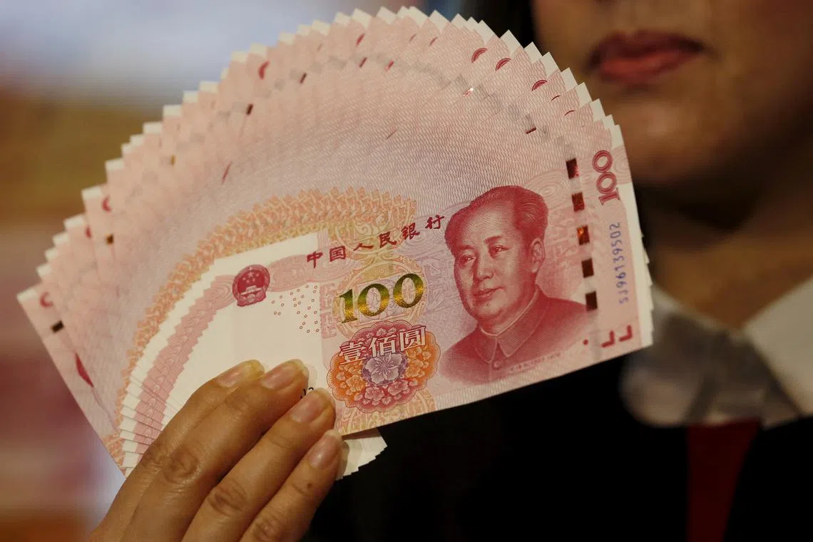 FILE PHOTO: A staffer poses with 2015 edition of the 100 renminbi notes at the Bank of China Tower in Hong Kong, China November 12, 2015.      REUTERS/Bobby Yip/File Photo
