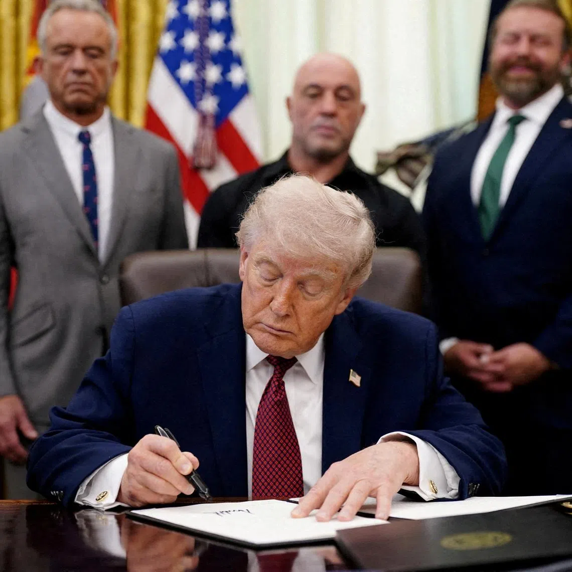 FILE PHOTO: U.S. President Donald Trump signs an executive order encouraging more research into ibogaine, next to U.S. Health and Human Services (HHS) Secretary Robert F. Kennedy Jr., Joe Rogan, and Americans for Ibogaine CEO W. Bryan Hubbard, in the Oval Office of the White House in Washington, D.C., April 18, 2026. REUTERS/Nathan Howard/File Photo