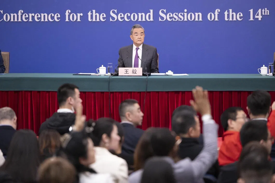 Chinese Foreign Minister Wang Yi looks on as reporters raise their hands to ask questions, during a press conference in Beijing.