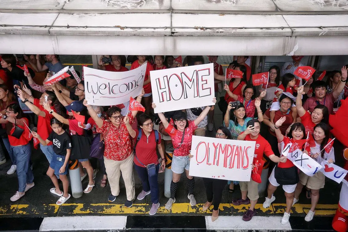 Supporters waving at Team Singapore?s Paris 2024 Olympians as the open top bus passes by MBS during the One Team Singapore celebratory parade on Aug 14, 2024. ST PHOTO: KEVIN LIM dgbus14