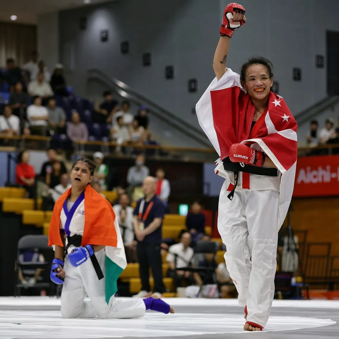 Tiffany Teo of Singapore raising her fist, while a disconsolate Suchika Tariyal of India sank to her knees, after being announced the winner of the mixed martial arts women's tradition (60kg) semifinal of the Aichi-Nagoya 2026 Asian Games at the Nagoya City Inae Sports Centre in Nagoya, Japan on Sept 21, 2026. ST PHOTO: KEVIN LIM pixag21