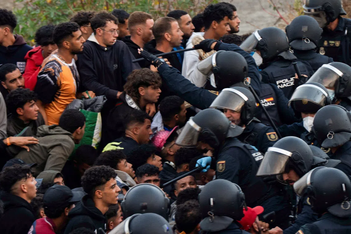Police escort migrants from Benitez Beach to be relocated to the camp set up at the port of Ceuta, Spain, September 18, 2026. REUTERS/ Anna Surinyach